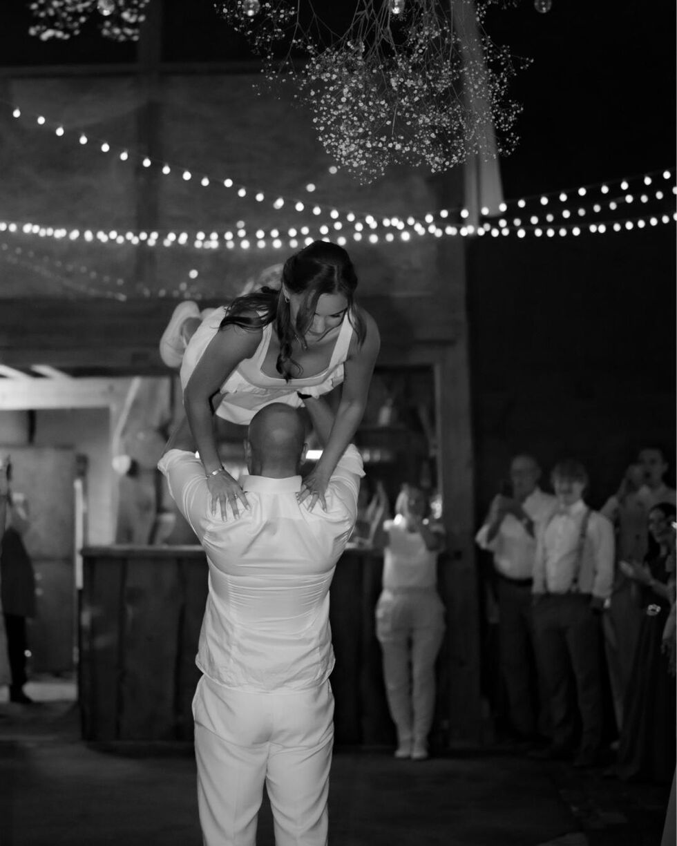 Eröffnungstanz der Hochzeit: Die Braut wird in einer Dirty-Dancing-Hebefigur hochgehoben, umgeben von Gästen und Lichterketten.